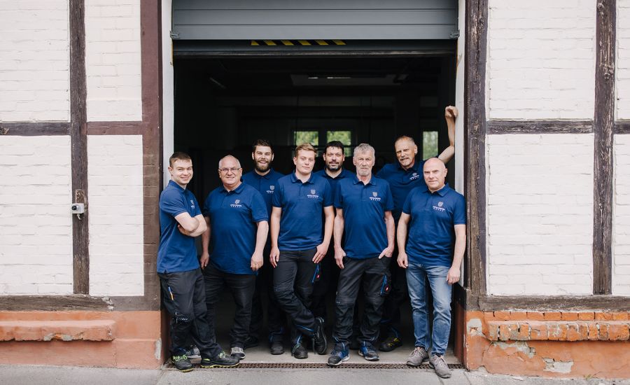 Teamfoto am Werkstatteingang – Fachkräfte aus Konstruktion, Fertigung und Werkzeugbau vereint.
